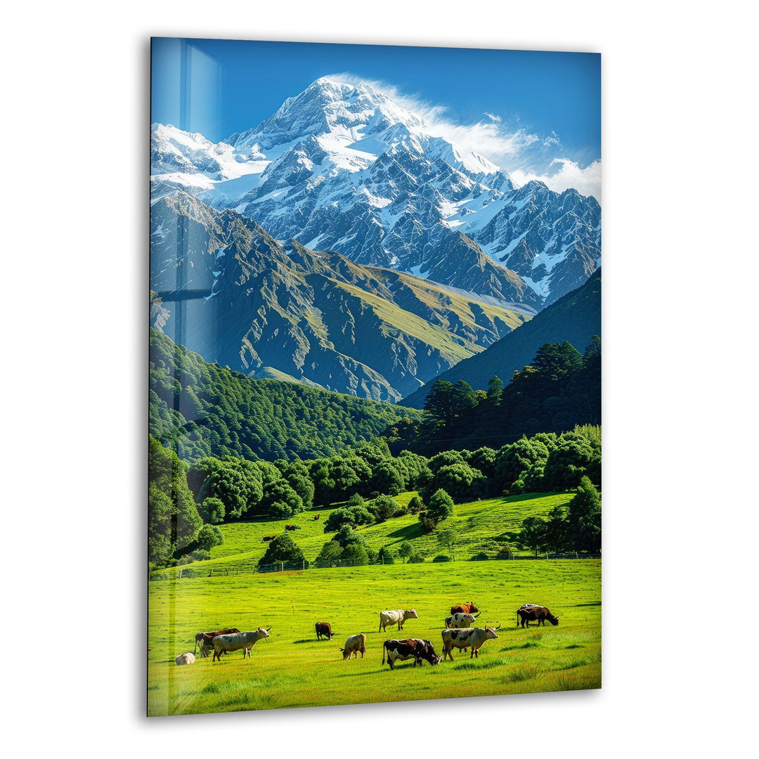 A breathtaking alpine meadow with grazing cattle and towering snow-capped mountains in the background.