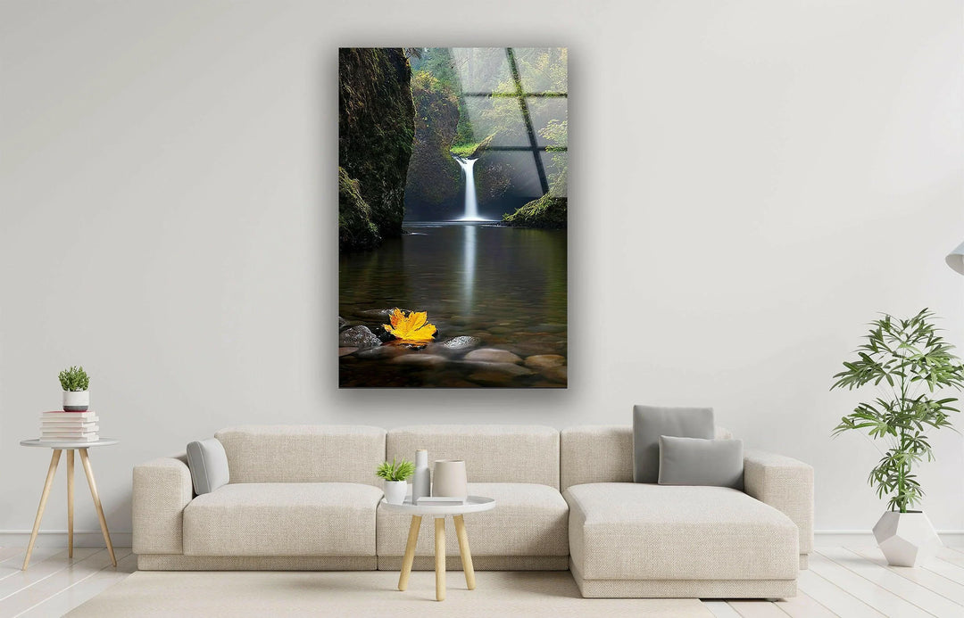 Soothing waterfall scene with vibrant greenery and a floating autumn leaf.