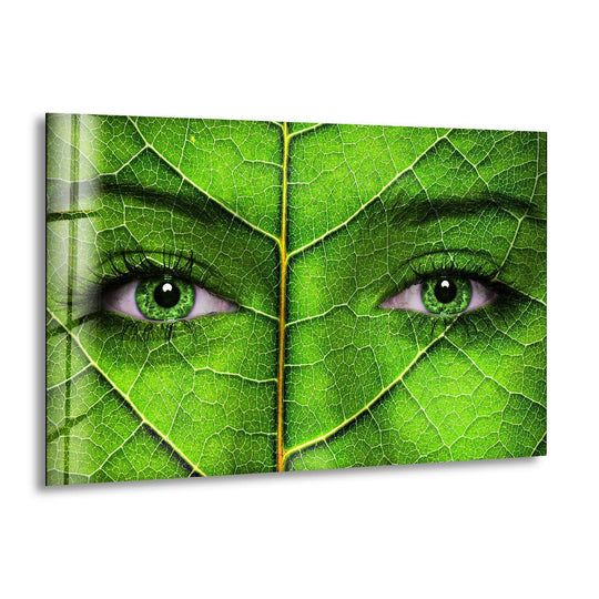A woman's eyes, with vibrant green irises, are the focal point on this striking art from glass featuring a detailed leaf texture.
