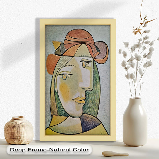 A softly lit tabletop displays a petite woven vase, a minimalist wooden piece, and a framed oil painting reproduction print showcasing an abstract female portrait.