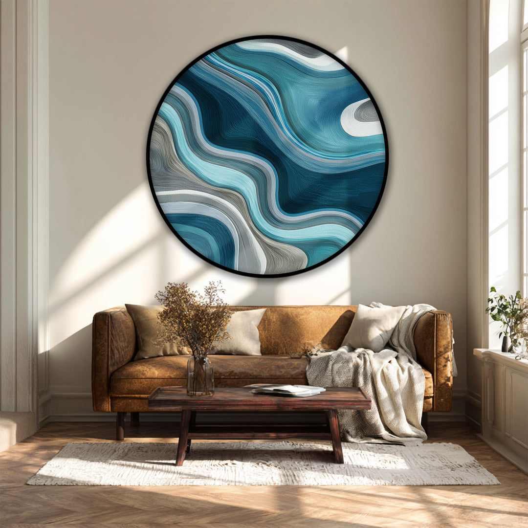 The flowing, cream-colored negative space accentuates the swirling teal waves in this round canvas artwork, a modern abstract canvas print mounted above a sofa.