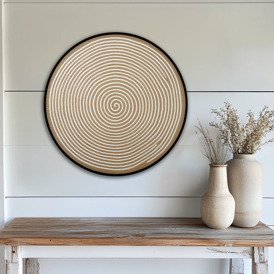 Realistic detail showcases a modern abstract wall art piece, a round golden spiral minimalist hanging canvas print with fine textured lines, mounted above a wooden table.