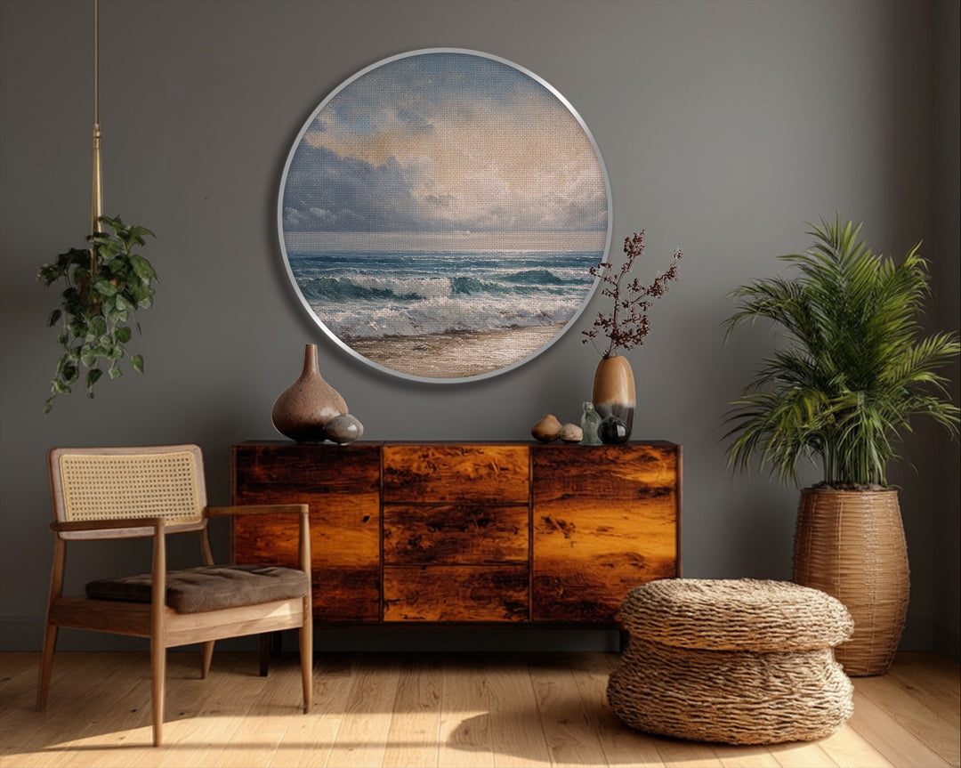 Rough canvas artwork texture is visible in this round print of coastal waves meeting the sandy shore, a classic seascape surface.