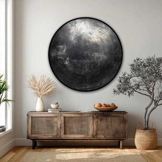 The stillness of the modern, minimal interior emphasizes the beauty of the industrial black textured abstract circle hanging canvas, creating a calming focal point.