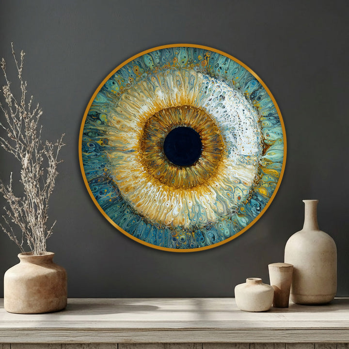 Circular canvas art showcases a stylized eye with concentric geometric forms, blending gold and blue hues in an abstract composition for unique wall decor.