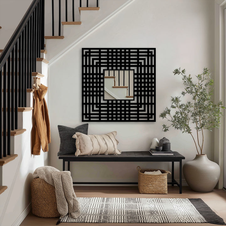 Set against a bright entryway, a geometric frame mirror showcases the blurred reflection of a staircase, enhancing the stained glass wall mirror aesthetic.