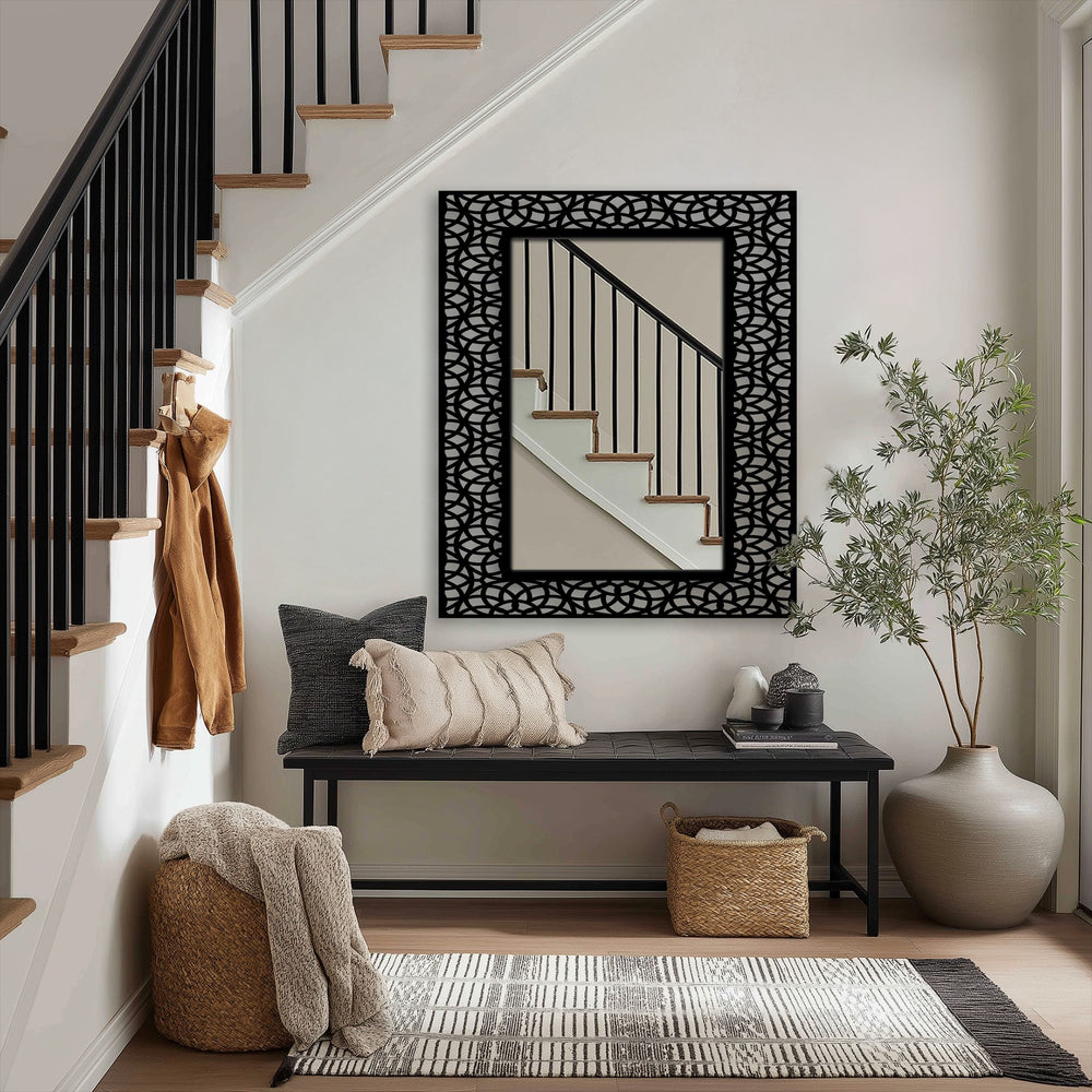 The darkest area frames the reflected stairs within a modern stained glass wall mirror that features a black interlocking arc decorative metal art pattern.