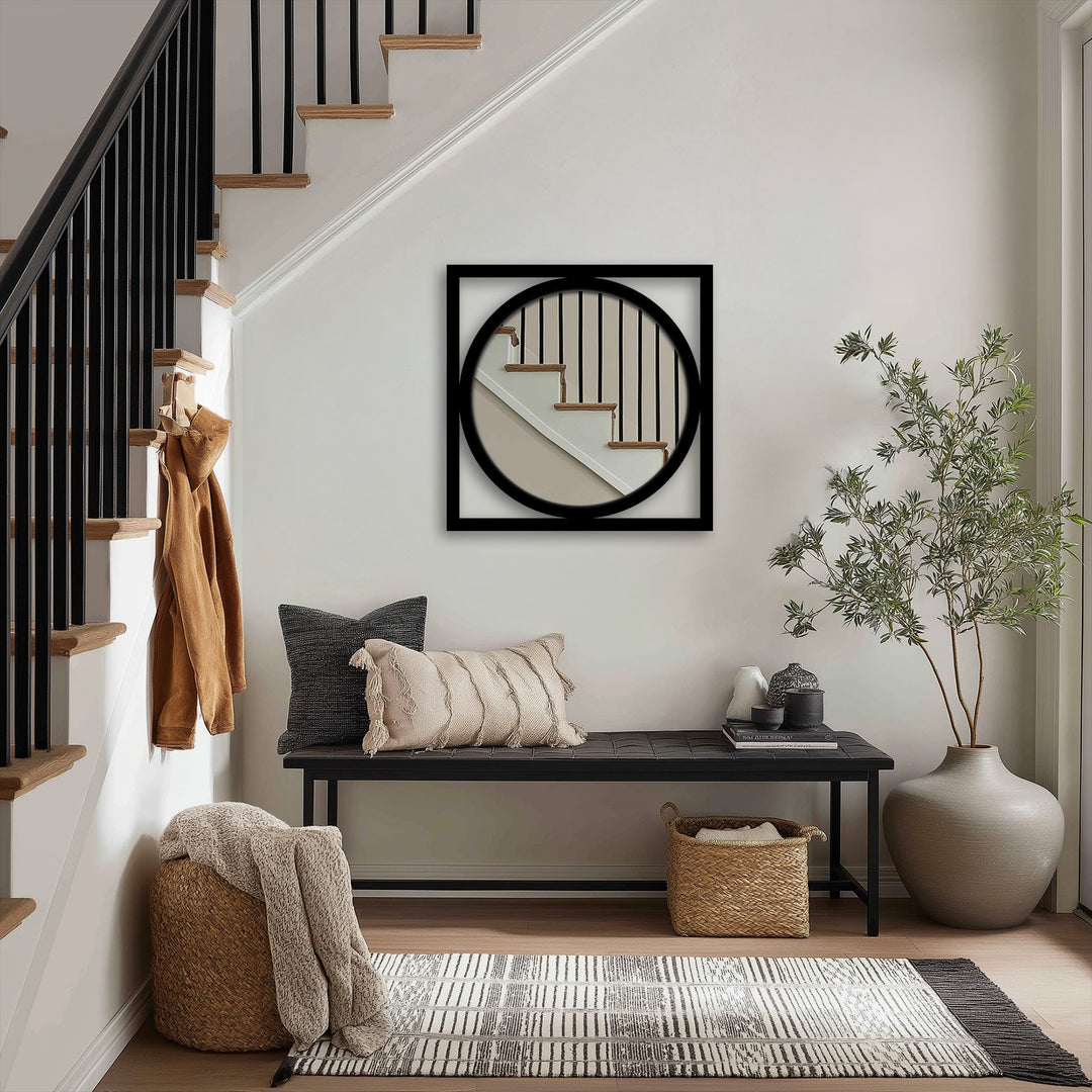 Black framed square mirror with round interior presents a captivating display, showcasing unique metal wall art as the loudest element in a modern entryway.