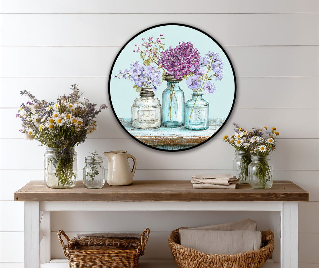 Visible depth and layers are created by the arrangement of floral vases in this round oil painting wall art depicting pastel wildflowers.