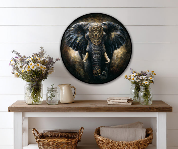 Warm color temperature accentuates the dark majestic round oil painting art prints of an elephant with a tribal mask, set against a cool white backdrop.