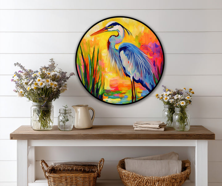 White wall's negative space surrounds the radiant marsh round oil painting artwork, highlighting the colorful heron in a vibrant, artistic display.