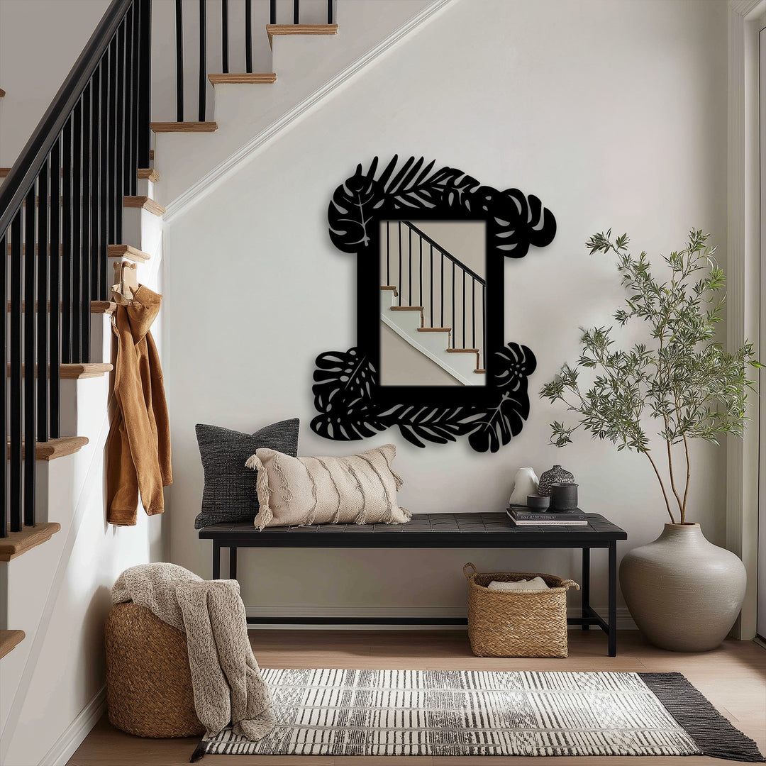 Cool color temperature highlights the black decorative metal art tropical leaf frame wall mirror above a bench with pillows, basket, and plant.