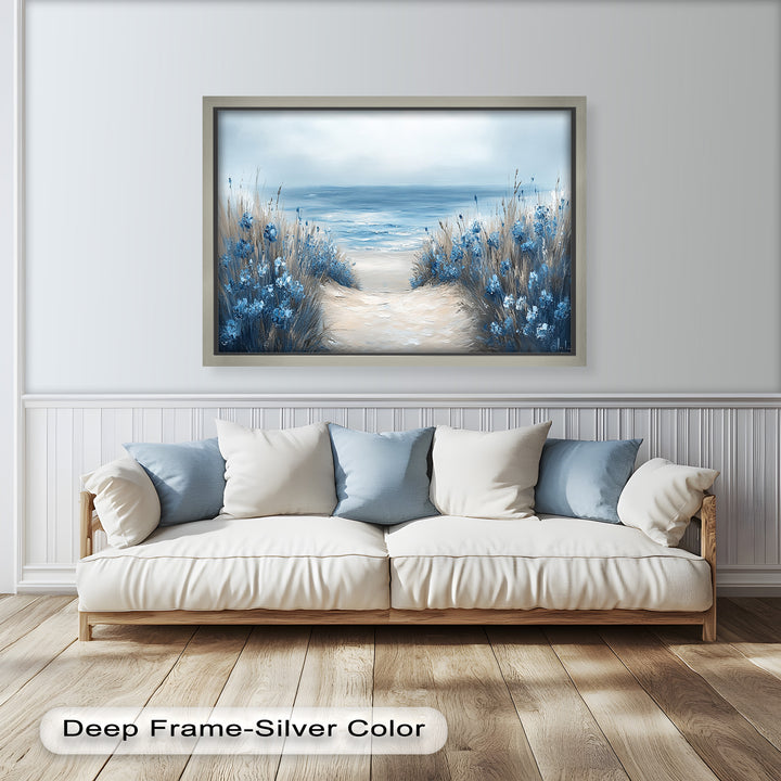Tranquil beach view with tall grasses and blue blossoms on either side of a path leading to the quiet sea.