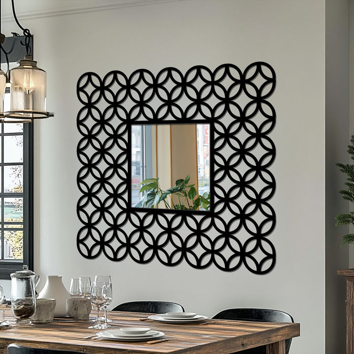 Minimal color saturation enhances the striking black interlocking ring patterned frame around this square stained glass wall mirror, adding a touch of geometric elegance.