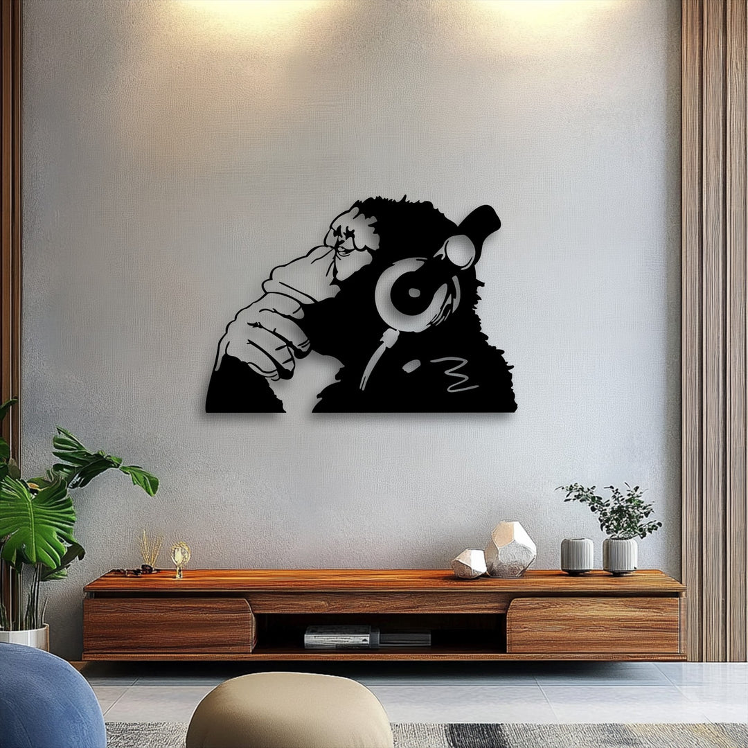 The sleek, smooth surface of the decorative metal art outlines an urban monkey wearing headphones on a subtly textured wall.