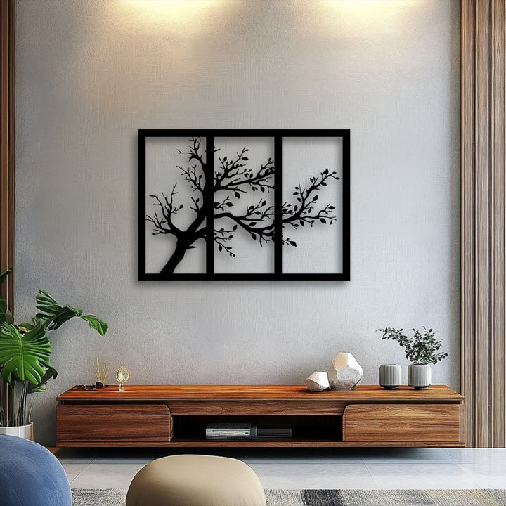 Warm color temperature lighting highlights the minimalist tree silhouette triptych metal art for wall against a cool gray wall.