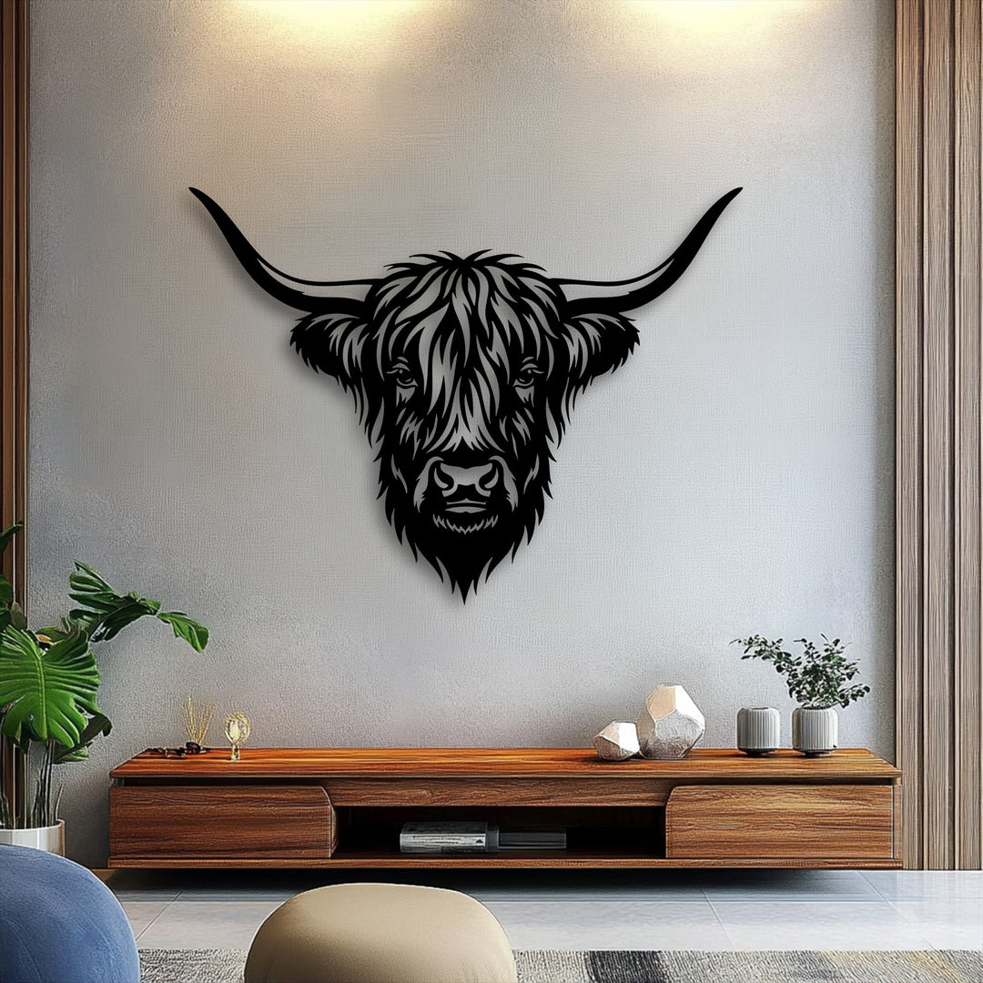 The textured light gray wall background with warm lighting beautifully displays the rustic Highland bull metal artwork, framed by wooden panels.