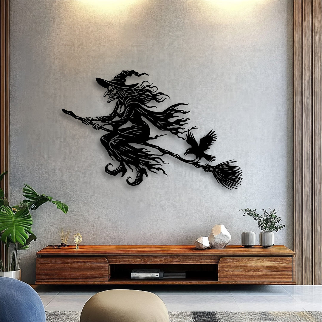 A large potted green plant and stylish seating are prominent in the foreground, framing the captivating flying witch metal artwork.