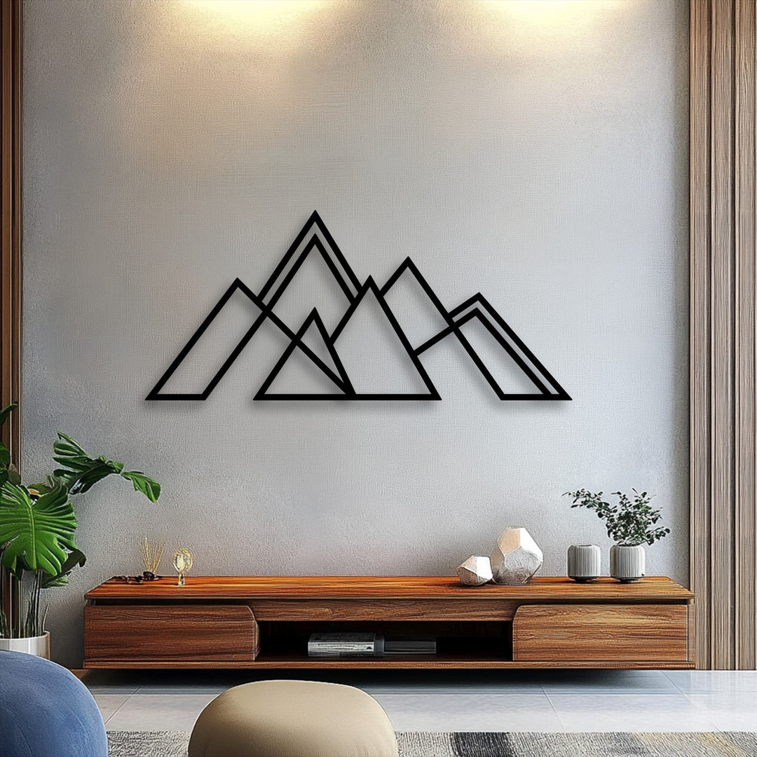 A muted gray wall highlights striking black geometric mountain decorative metal art, paired with warm wooden textures and subtle lighting.