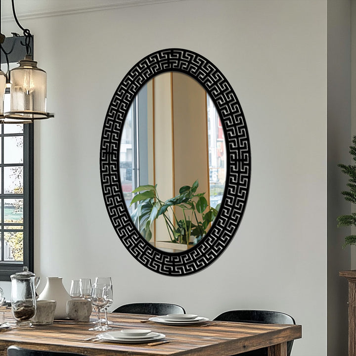 Organic forms of the plant's reflection soften the geometric decorative mirror, contrasting nature with the Greek key patterned frame.