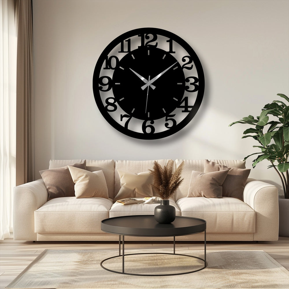 The modern black metal wall clock shows a stark transition between colors, highlighting the decorative metal art numbers against the light wall.