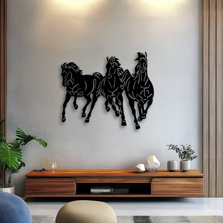 The striking silhouette of three dynamic, galloping horses crafted from black metal art for wall dramatically stands out against the textured wall.