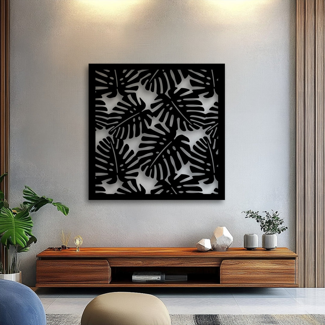 Bold black Tropical Monstera Leaf Pattern metal wall decor prominently displayed on a light textured wall.