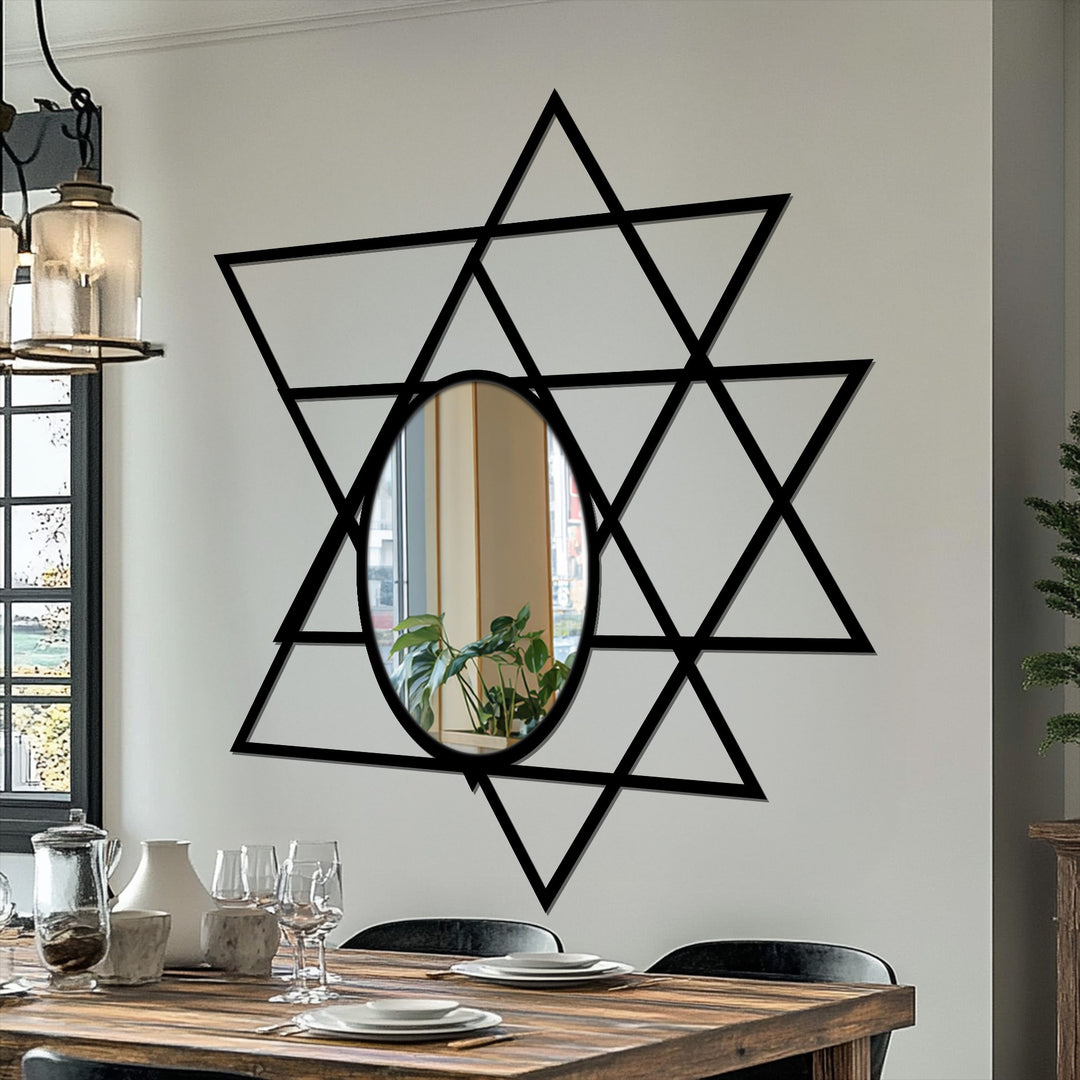 Vertically oriented oval modern mirror reflects a plant within a Star of David formed by black intersecting triangles.