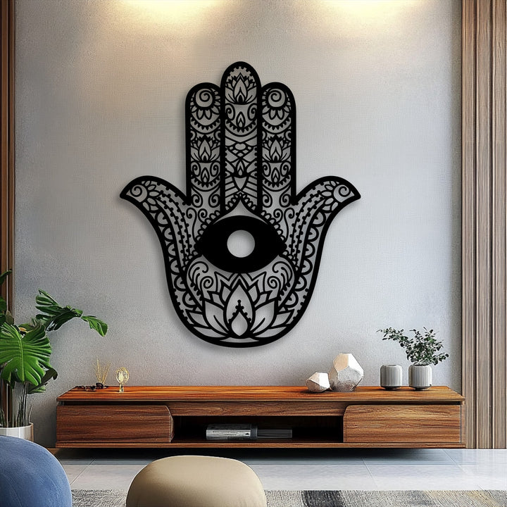 A light gray textured wall, softly illuminated from above, serves as a refined background for the intricate hamsa hand metal artwork.