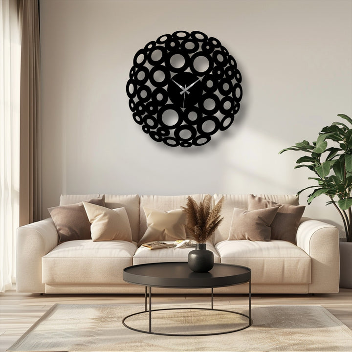 Illuminated by the light, the interior circles of the Bubble Circle decorative metal art wall clock stand out against the contrasting black metal ring design.