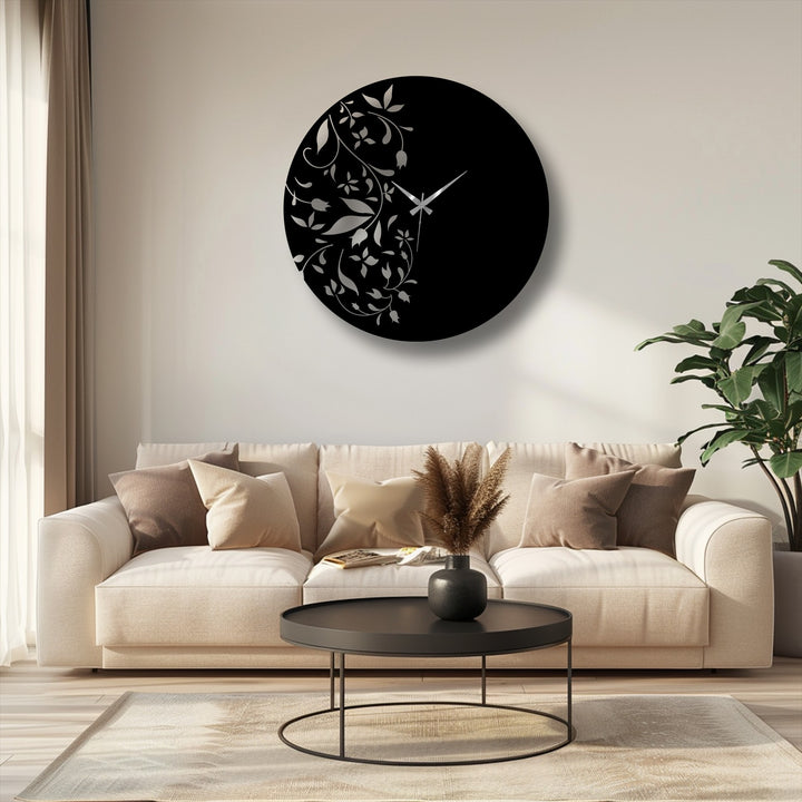 A circular decorative metal art wall clock showcases a geometric floral leaf design with its precise, minimalist hands displaying time against a stark black background.
