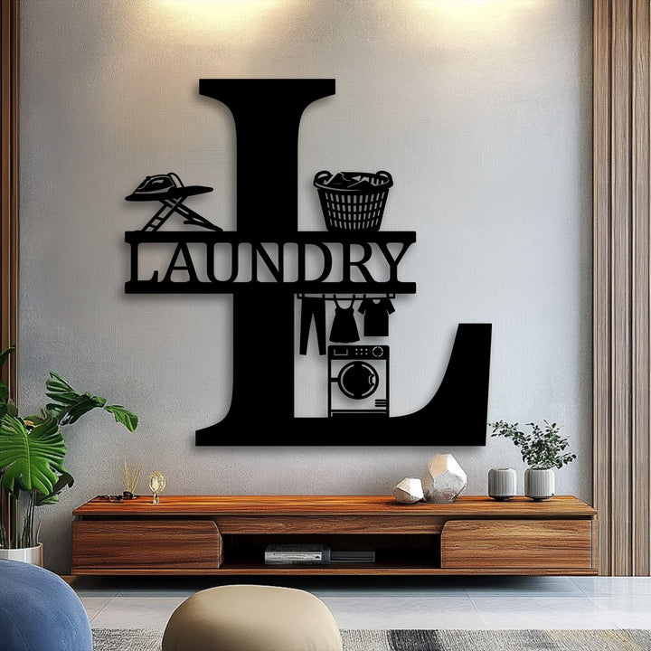 The metal artwork showcasing a personalized laundry monogram in an 'L' shape is highlighted by warm overhead lighting on a textured cool grey wall.