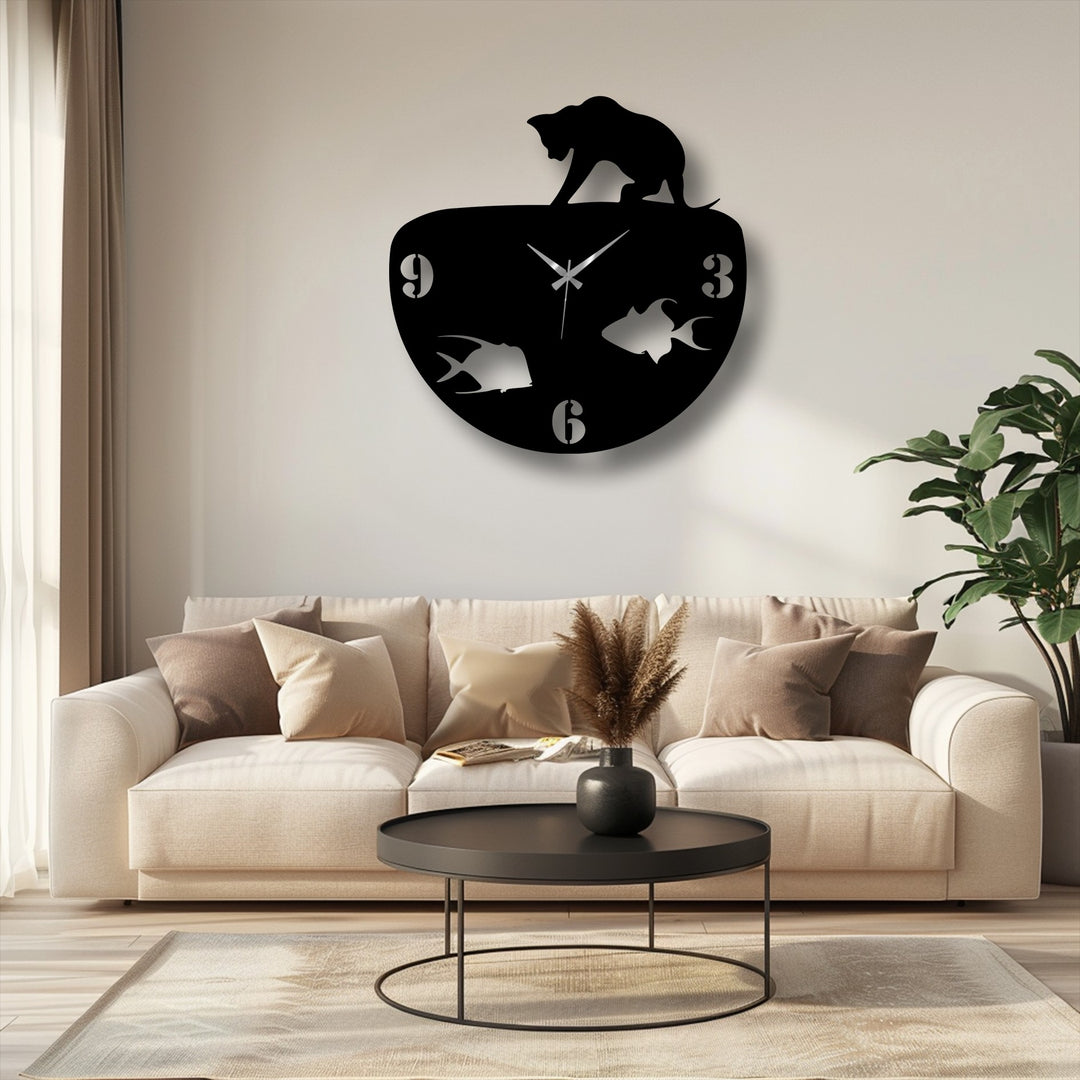 An abstractly shaped metal wall decor clock features a stylized cat playfully reaching over its top, with cut-out fish figures for the numbers.