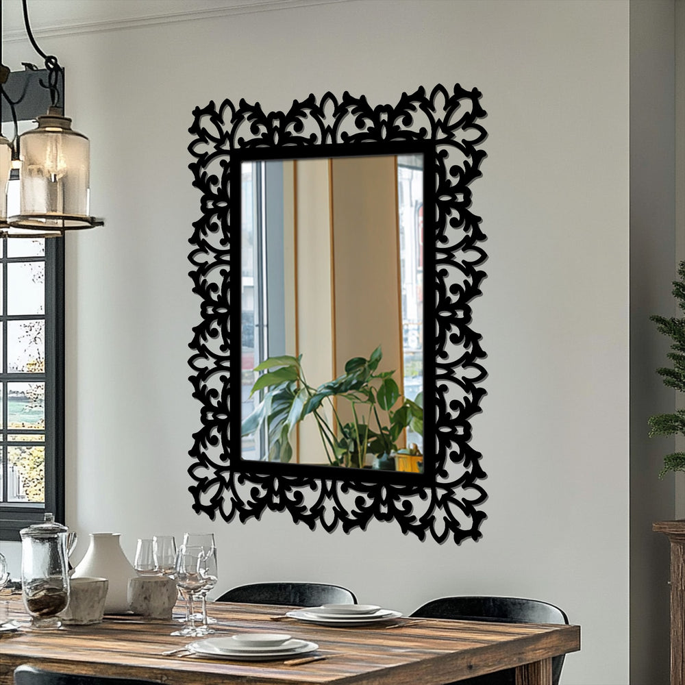 Brightest area shows the reflected window light within this ornate rectangular mirror, framed in decorative metal art with an elegant botanical scroll design and a black frame.