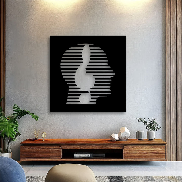 A bold black decorative metal art piece commands attention, displaying an abstract human head profile with distinctive striped lines.