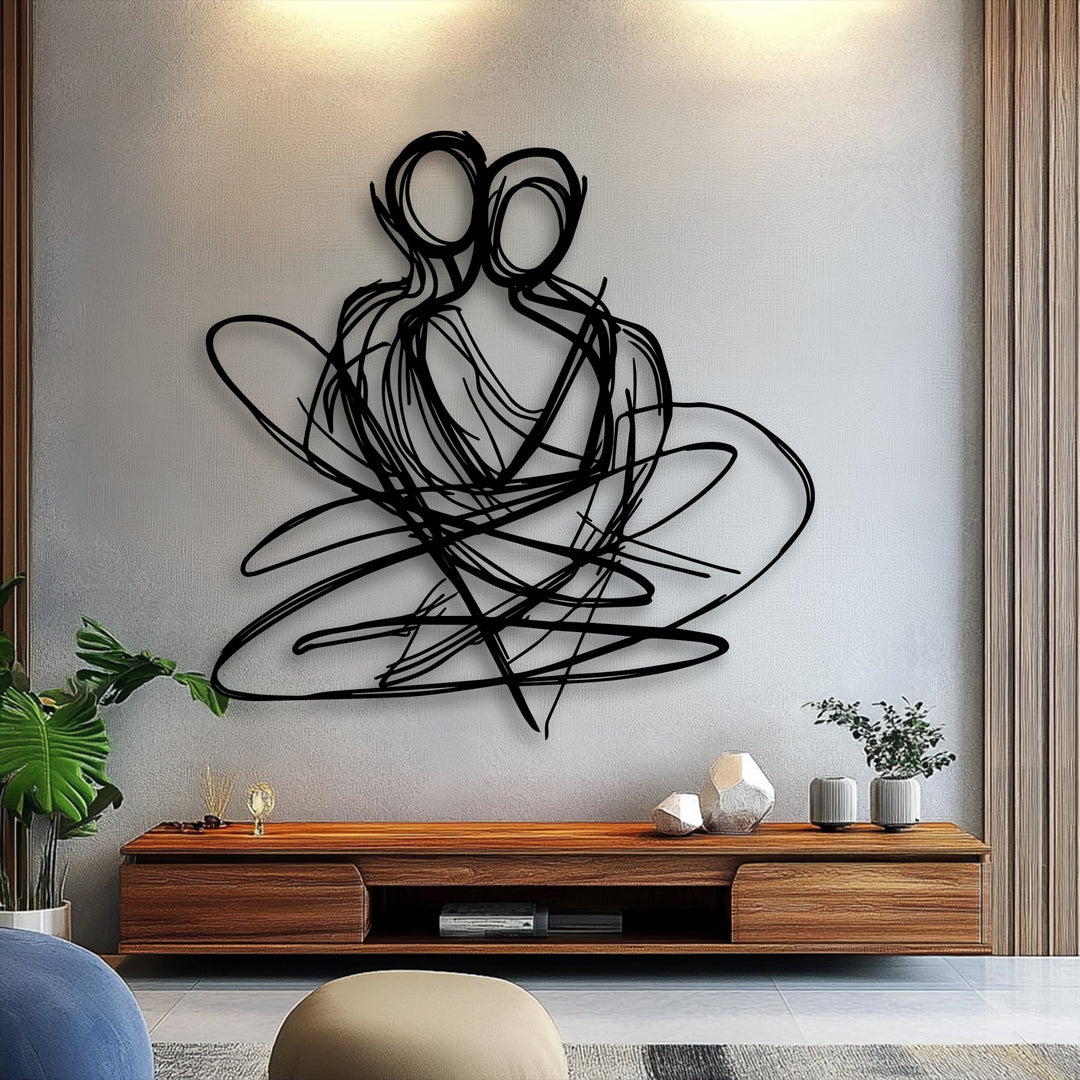 The subtly textured light grey wall with warm overhead lighting in the background provides a striking contrast for the elegant metal artwork.