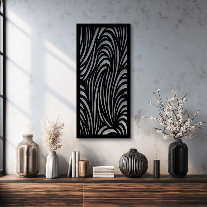 Layered flowing stripes form an abstract wave pattern within the striking black metal wall decor, adding significant depth to the textured wall above a wooden dresser.