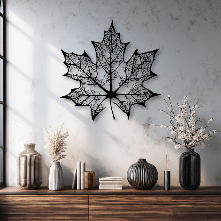 A subtly textured, off-white wall, illuminated by sunlight and window pane shadows, provides a bright canvas for the metal artwork.