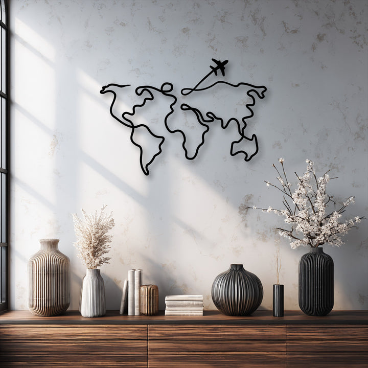 A sleek, black minimalist world map decorative metal art with an airplane path prominently adorns a light textured wall.