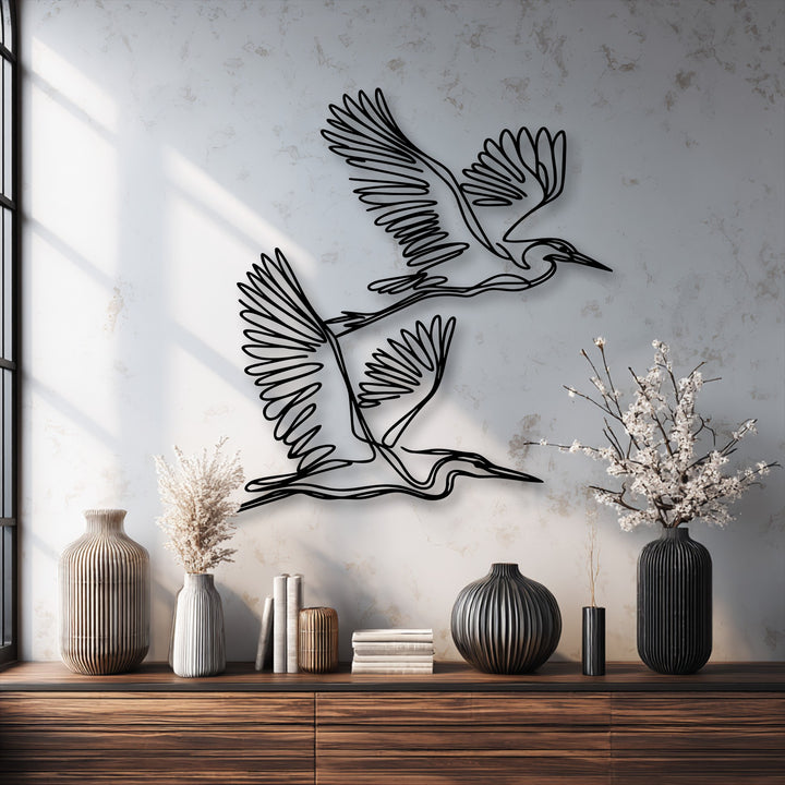 Graceful minimalist black outline herons form elegant metal art for wall decor against a subtly textured light gray background.