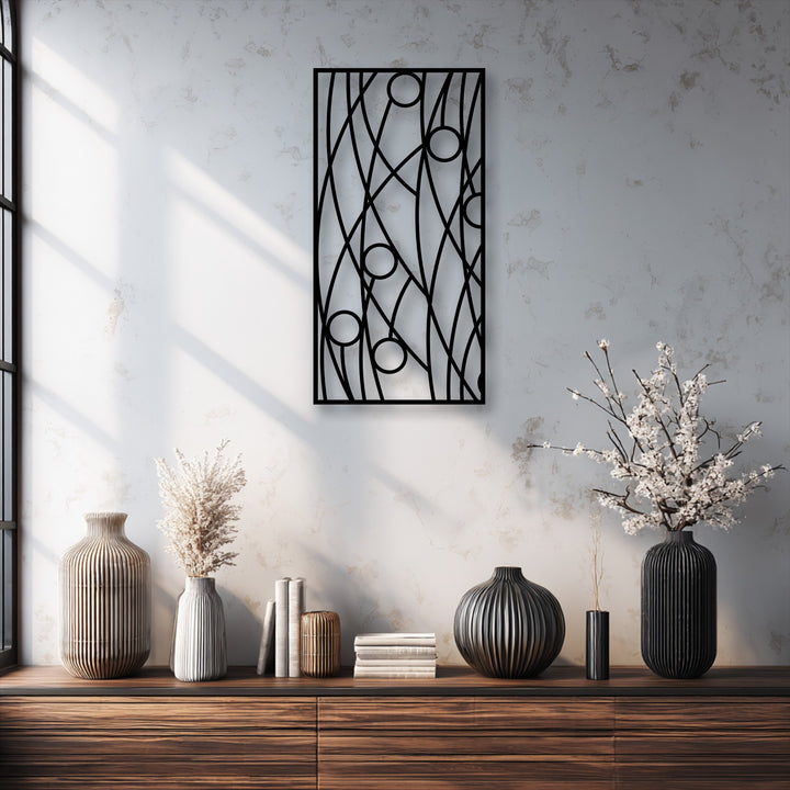 An abstract black panel of unique metal wall art with geometric lines and circles serves as a modern minimalist centerpiece.