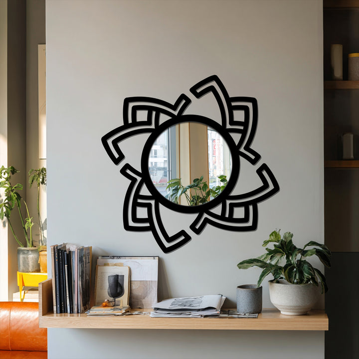 Decorative mirror featuring an abstract rotating metal frame with a dynamic design serves as the focal point on a neutral-toned wall above a wooden shelf.