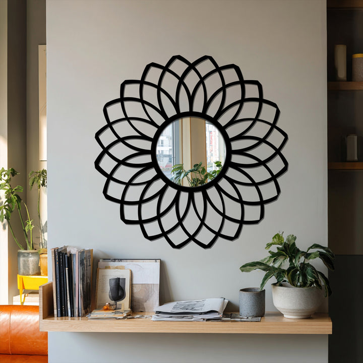 Warm lighting highlights the black frame of this layered petal framed wall mirror, complementing the shelf and potted plants.
