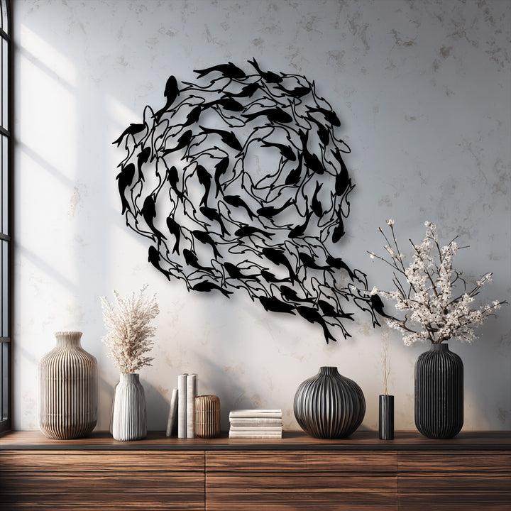 A large, circular black metal decoration wall art depicting koi fish swimming in a continuous, flowing pattern on a textured white wall.