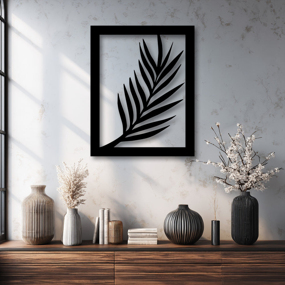 The crisp black edge and sharp borders of the minimal palm leaf metal artwork create a striking silhouette against the textured wall.