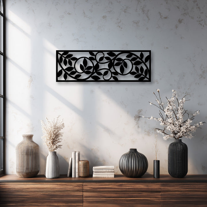 The focal point is a unique metal wall art panel, a striking black flowing botanical vine pattern with leaves and circles on a textured wall.