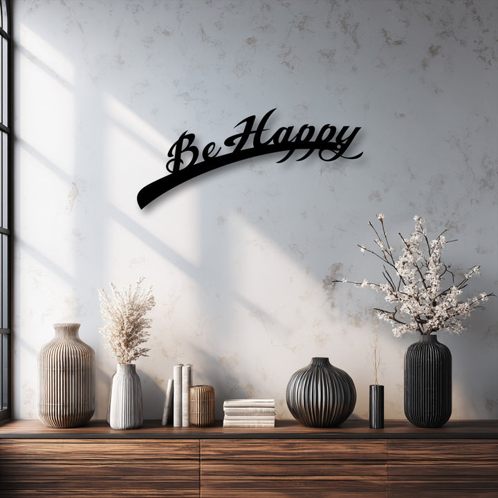 The subdued color saturation highlights the striking black Be Happy decorative metal art against the muted background, creating a calm aesthetic.
