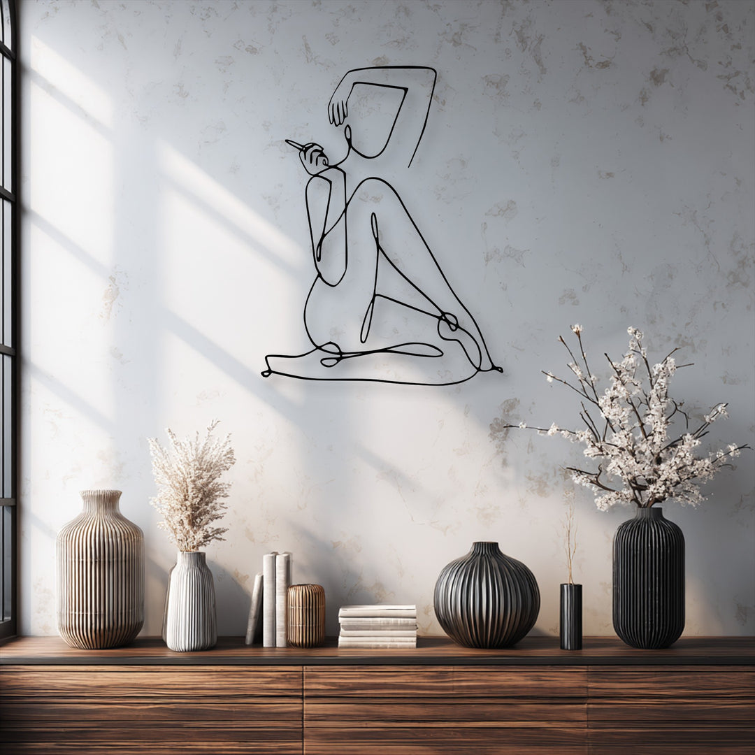 The striking black minimalist female line art, an elegant abstract figure, serves as decorative metal art on a textured white wall.