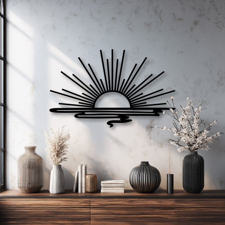 Focusing on the radiant horizon, this minimalist black metal wall decor depicts a stylized sunrise with distinct rays and a shimmering reflection.
