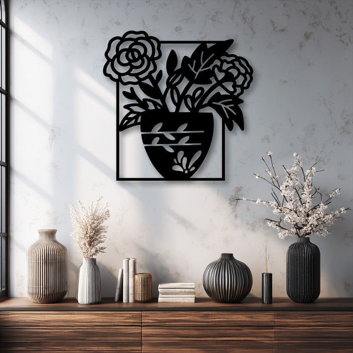 The realistic detail of the black metal wall decor creates striking shadows and depth, beautifully depicting a floral vase silhouette on a textured wall.